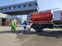 Übung AB Übungstank Feuerwehrangehörige in Schutzanzügen tragen eine Auffangwange an den AB Übungstank, der eine Flüssigkeit austritt