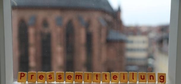 Symbolbild Pressemitteilung (Foto: Stadt HD) Das Wort "Pressemitteilung" in Scrabble Buchstaben auf eine Fensterbank gelegt. Die Heiliggeistkirche ist im Hintergrund zu sehen.