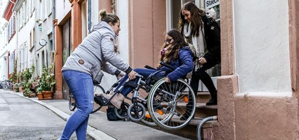 Barrierefreiheit in der Altstadt (Foto: Pellner) Zwei Frauen tragen eine Frau im Rollstuhl eine Treppe hinunter