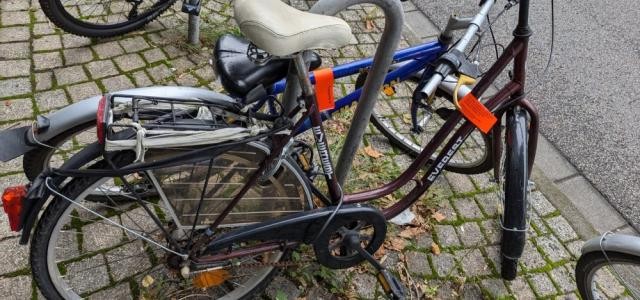 Zwei Fahrräder sind an einem Fahrradständer abgestellt. Beide wurden mit roten Banderolen markiert.