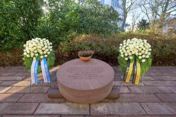 Ein großer runder Sandstein, rechts und links mit Kränzen zum Gedenken Ein großer runder Sandstein, rechts und links mit Kränzen zum Gedenken