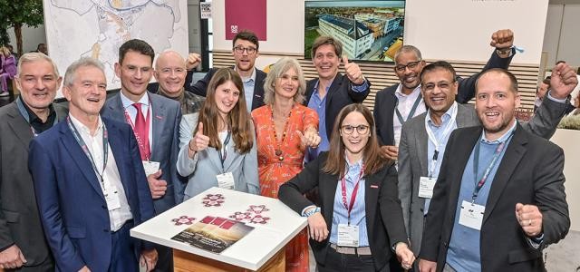 Zehn Menschen stehen vor Messewänden.