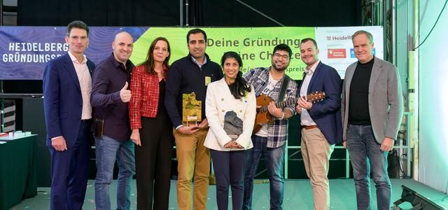 Zehn Menschen lächeln auf einer Bühne in die Kamera.