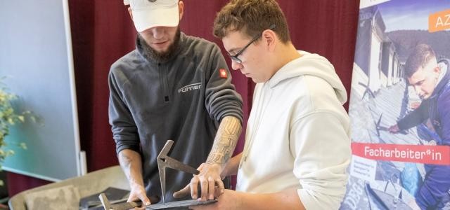 Zwei Männer beugen sich über ein Schieferstück.