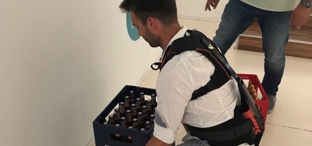 Handwerker Denis Waskey hebt mit Unterstützung des Exoskeletts gleich zwei Getränkekästen.