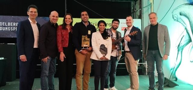 Eine Gruppe von Menschen steht auf einer Bühne und hat sich für die Kamera aufgestellt.