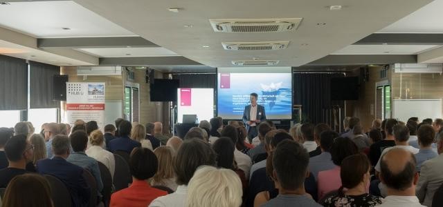 Marc Massoth steht vor einem Publikum und spricht zu diesem.