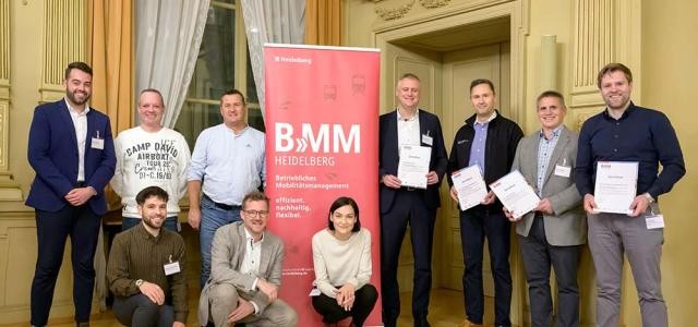 Gruppe von Menschen vor und neben dem roten BMM-Aufsteller