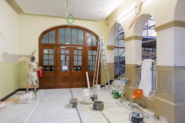 An der Marie-Marcks- und der Wilckensschule werden in den Sommerferien die Haupttreppenhäuser saniert – eine von zahlreichen Modernisierungsmaßnahmen, die in der schulfreien Zeit an den Heidelberger Schulen laufen. (Foto. Rothe) Malerarbeiten in einem Schulraum mit hohen Wänden und Holztür