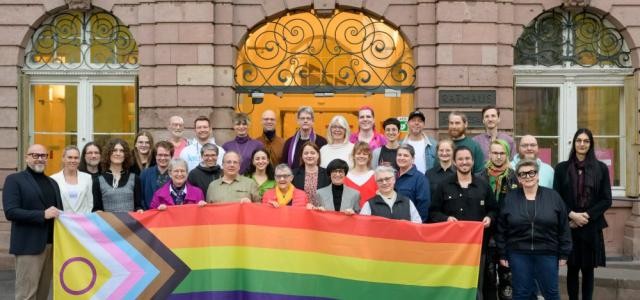 Gruppenfoto mit einer Progress Pride Flagge.