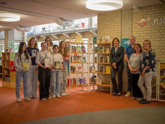 Die Literaturscouts, hier vertreten durch Mirelle Walter (v.l.), Mariann Krauss, Lilli Gulbins, Carolin Durani, Ella Dilan und Ava Schnell, präsentieren das neue Regal mit ihren Empfehlungen in der Stadtbücherei. Kulturbürgermeisterin Martina Pfister (v.l.), Markus Lautenschläger (Geschäftsführer der Manfred-Lautenschläger-Stiftung), Literaturscouts-Mentorin Silvia Schröer und Büchereidirektorin Christine Sass freuen sich über das neue Angebot und sind gespannt auf weitere Projekte der jungen Bücherfans. (Foto: Tobias Dittmer) Gruppenfoto der Literaturscouts
