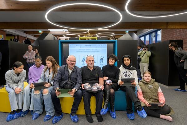 Bei der Eröffnung des neuen digitalen Zentrums „Fuchsbau“: Schülerinnen der Waldparkschule mit (Mitte v.r.) Bürgermeisterin Stefanie Jansen, Rektor Thilo Engelhardt und dem Leiter des Hochbauamts Harald Heußer. (Foto: Rothe) Junge und ältere Menschen auf Sitzgelegenheiten blicken in die Kamera.