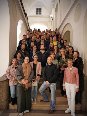 Starkes Engagement für die Interesse von Eltern und Kindern in den Heidelberger Kitas: der Gesamtelternbeirat mit der scheidenden GEB-Vorsitzenden Dr. Eva Fritzsching (2. Reihe 2.v.r.) und Myriam Lasso, Leiterin des Kinder- und Jugendamts (1. Reihe 1.v.r.). (Foto: Stadt Heidelberg) Eine große Gruppe Menschen posiert fröhlich für ein Gruppenfoto auf einer Ste steilen Treppe im Heidelberger Rathaus.