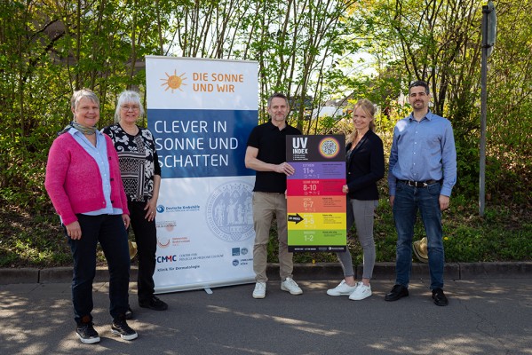 V.l.n.r.: Frau Susanne Hering (Amt für Sport und Gesundheitsförderung), Frau Frau Dr. Grosskopf-Kroiher (Leiterin des Hautkrebspräventionsprojekts DIE SONNE UND WIR (Universität zu Köln/Uniklinik Köln), Andreas Bieber (stellv. Amtsleiter ASZ Heidelberg), Carina Annalena Jung (Projektleiterin WATCH OUT), Andreas Kappel (Personal- und Organisationsamt). (Foto: Stadt Heidelberg) Fünf Personen stehen vor einem Aufsteller mit der Aufschrift "Clever in Sonne und Schatten".