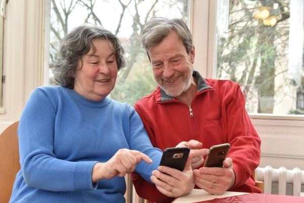 Gemeinsam digital am Ball blieben können Seniorinnen und Senioren beim neuen Digitalstammtisch im Seniorenzentrum Weststadt/Südstadt. (Foto: Peter Dorn) Eine Seniorin und ein Senior sitzen zusammen am Tisch und zeigen sich gegenseitig Inhalte auf ihrem Smartphone.
