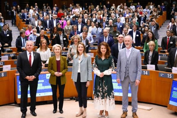 Heidelbergs Oberbürgermeister Eckart Würzner (3. Reihe, Mitte rechts) und 150 weitere europäische Bürgermeisterinnen und Bürgermeister beim Meet&Greet mit EU-Parlamentspräsidentin Roberta Metsola (vorne, Mitte), EU-Kommissionspräsidentin Ursula von der Leyen (2. von links), Kata Tüttő (Präsidentin des Europäischen Ausschusses der Regionen, 2. von rechts), Attila Péterffy (Bürgermeister von Pécs, links) und Seamus Hoyne (Dekan an der Technological University of the Shannon Irland, rechts). (Foto: European Union / John Thys) Zu sehen sind eine Vielzahl von Personen in einem halbkreisförmigen Versammlungssaal.