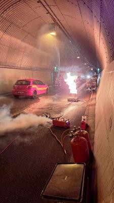 Für die Übung im Schlossbergtunnel wurde ein kleineres, aber dennoch anspruchsvolles Brandszenario angenommen: Aufgrund eines Verkehrsunfalles war ein Pkw in der Mitte des Tunnels in Brand geraten, der Fahrer war in seinem Fahrzeug eingeklemmt. (Foto: Feuerwehr Heidelberg) Brennender Pkw in der Mitte des Schlossbergtunnels