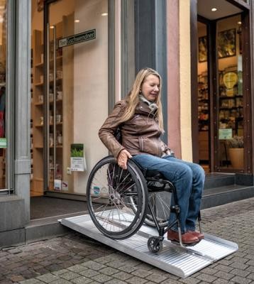 Eine Rollstuhlfahrerin verlässt über eine mobile Rampe ein Geschäft. Eine Rollstuhlfahrerin nutzt eine mobile Rampe (Foto: Dittmer)
