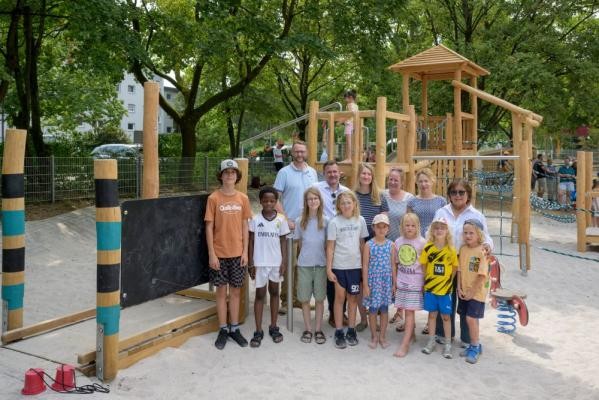 Bürgermeister Raoul Schmidt-Lamontain (hintere Reihe, 2.v.l.) eröffnete den sanierten Kinderspielplatz Baden-Badener Straße im Hasenleiser gemeinsam mit Kindern sowie Vertreterinnen und Vertretern der Stadt Heidelberg. In der hinteren Reihe von links – Andreas Caelers (Landschafts- und Forstamt), Astrid Clausen (Büro für Inklusion im VbI, zuständig für das Projekt SPIN), Barbara Pfeiffer (Kinderbeauftragte Rohrbach), Angelika Kern und Juliah Rais-Morres (beide Landschafts- und Forstamt). (Foto Philipp Rothe) Kinder und Erwachsene stehen vor neuen Spielgeräten.