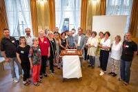 Eine Geburtstagstorte zum 25. Jubiläum: Ihren Einsatz für ein kinderfreundliches Heidelberg feierte Oberbürgermeister Prof. Dr. Eckart Würzner (7.v.r.) mit Kinderbeauftragten aus 25 Jahren bei einem Empfang am 13. Mai. (Foto: Bäcker) Gruppenfoto Weitwinkel vor Torte