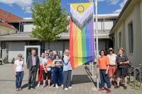 Mitglieder der Jugendgruppe „Queer-Youth“ hissten zusammen mit Vertreter*innen des Stadtteilvereins Kirchheim, des Internationalen Bund (IB) Heidelberg und Marius Emmerich von der städtischen Koordinationsstelle LSBTIQ+ (3.v.r.) die „Progress Flag“ vor dem Bürgerzentrum. (Foto: Rothe) Foto von Gruppe mit Regenbogenflagge