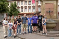 Die Teilnehmerinnen und Teilnehmer der 25. International Summer Science School Heidelberg 2022 kamen am ersten Tag zu einem gemeinsamen Foto auf dem Kornmarkt zusammen. (Foto: Philipp Rothe) Junge Erwachsene stehen vor einem Brunnen