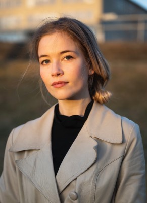 Die isländische Schriftstellerin María Elísabet Bragadóttir aus der UNESCO City of Literature Reykjavík ist die neue Literatur-Stipendiatin der Kulturstiftung Rhein-Neckar-Kreis e. V. und der UNESCO City of Literature Heidelberg. (Foto:Sigtryggur Ari Jóhannsson) Zu sehen ist ein Porträt der Schriftstellerin María Elísabet Bragadóttir. Sie steht vor einem verschwommenen Hintergrund und wird von goldenem Sonnenlicht angeleuchtet.