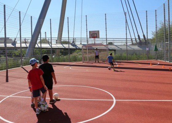 Kurz nach der Eröffnung des neuen Bolzplatzes an der Da-Vinci-Brücke wurde auch schon fleißig gekickt. (Foto: Stadt Heidelberg) Kinder mit Bällen auf dem Bolzplatz.