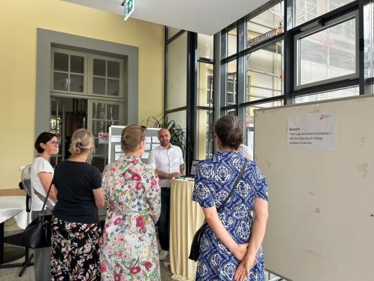 Bündnis für Ausbildung und Arbeit bietet Vorträge für Interessierte. (Bildnachweis: Stadt Heidelberg) Mitarbeiter stehen zusammen und hören einem Vortrag zu.