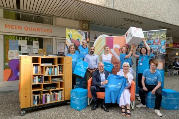 Oberbürgermeister Eckart Würzner (sitzend) stellte gemeinsam mit weiteren Beteiligten die Heidelberger Projekte bei den Freiwilligentagen 2026 vor: Annette Woithon (FreiwilligenAgentur Heidelberg; hinten von links), Wahid Watanyar und Lena Krug (Quartiersmanagement Hasenleiser), Hanni Derr und Samira Schork (OB-Referat der Stadt Heidelberg) sowie (vorne von links) Elfriede Lechner („Aktiv im Hasenleiser-Gruppe“ des Quartiersmanagements) und Eva-Maria Henrich (Metropolregion Rhein-Neckar). (Foto: Philipp Rothe) Oberbürgermeister Eckart Würzner und Freiwillige posieren neben einem Bücherregal