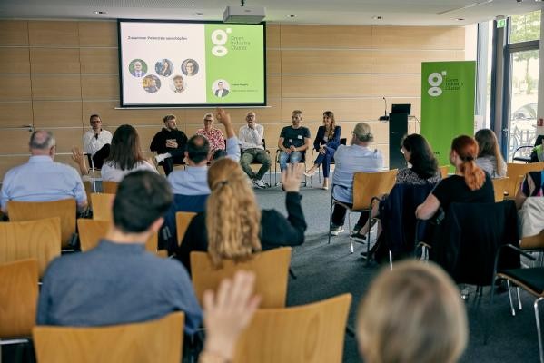 Spannende Diskussionen auf dem Podium. (Foto: Dietrich Bechtel) Blick von hinten über ein Publikum auf ein Podium mit sechs Personen.