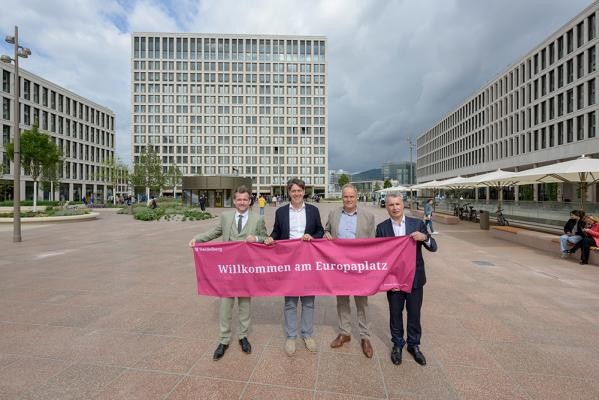 Ein Tag, der mit Sehnsucht erwartet wurde – am Freitag, 13. September 2024, fand die offizielle Eröffnung des Europaplatzes statt mit (von links) Bürgermeister Raoul Schmidt-Lamontain, Erster Bürgermeister Jürgen Odszuck, Oberbürgermeister Eckart Würzner und Kai. M. Dreesbeimdiek von der Gustav Zech Stiftung. (Foto: Philipp Rothe) Vier Männer in Anzug halten ein heidelbeerfarbenes Banner mit der Aufschrift "Willkommen am Europaplatz"
