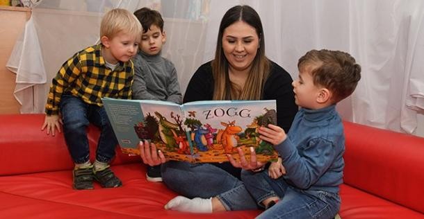 Kindertagespflege wird von der Stadt unterstützt (Foto: Dorn) Drei Kinder beim Vorlesen mit einer Erzieherin