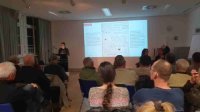 Die Referentin ist flankiert von 2 DGS-Dolmetscherinnen, der Saal ist gut gefüllt Die Referentin ist flankiert von 2 DGS-Dolmetscherinnen, der Saal ist gut gefüllt