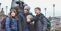 Drei Schulkinder stehen am Heidelberger Brückenaffen