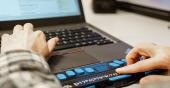 Person tippt mit Händen auf einer Braille-Tastatur eines Laptops (Foto: Arriens)