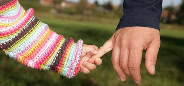 Kinderhand hält kleinen Finger einer Erwachsenenhand