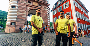 Drei junge Männer mit gelbem T-shirt vor der Alten Brücke